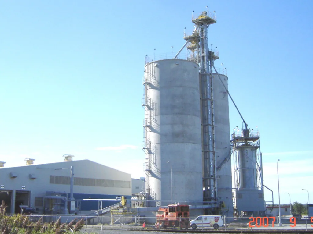 Silos et tour d’élévateur d’une usine d’éthanol, avec bâtiments industriels au premier plan.