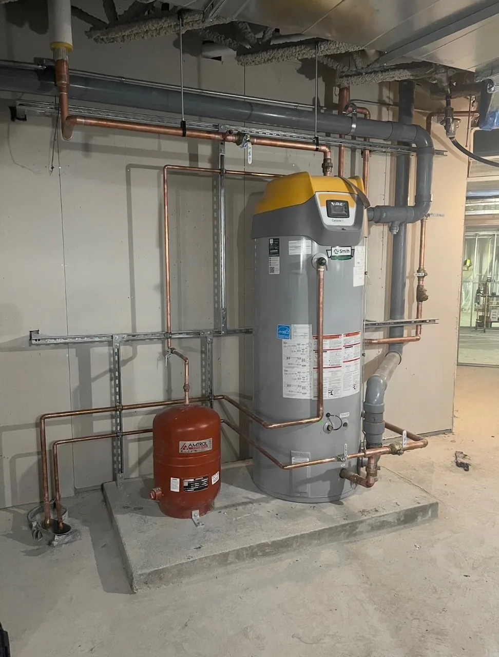 Équipement commercial de chauffage de l’eau avec tuyauterie en cuivre, réservoir d’expansion et composants muraux.