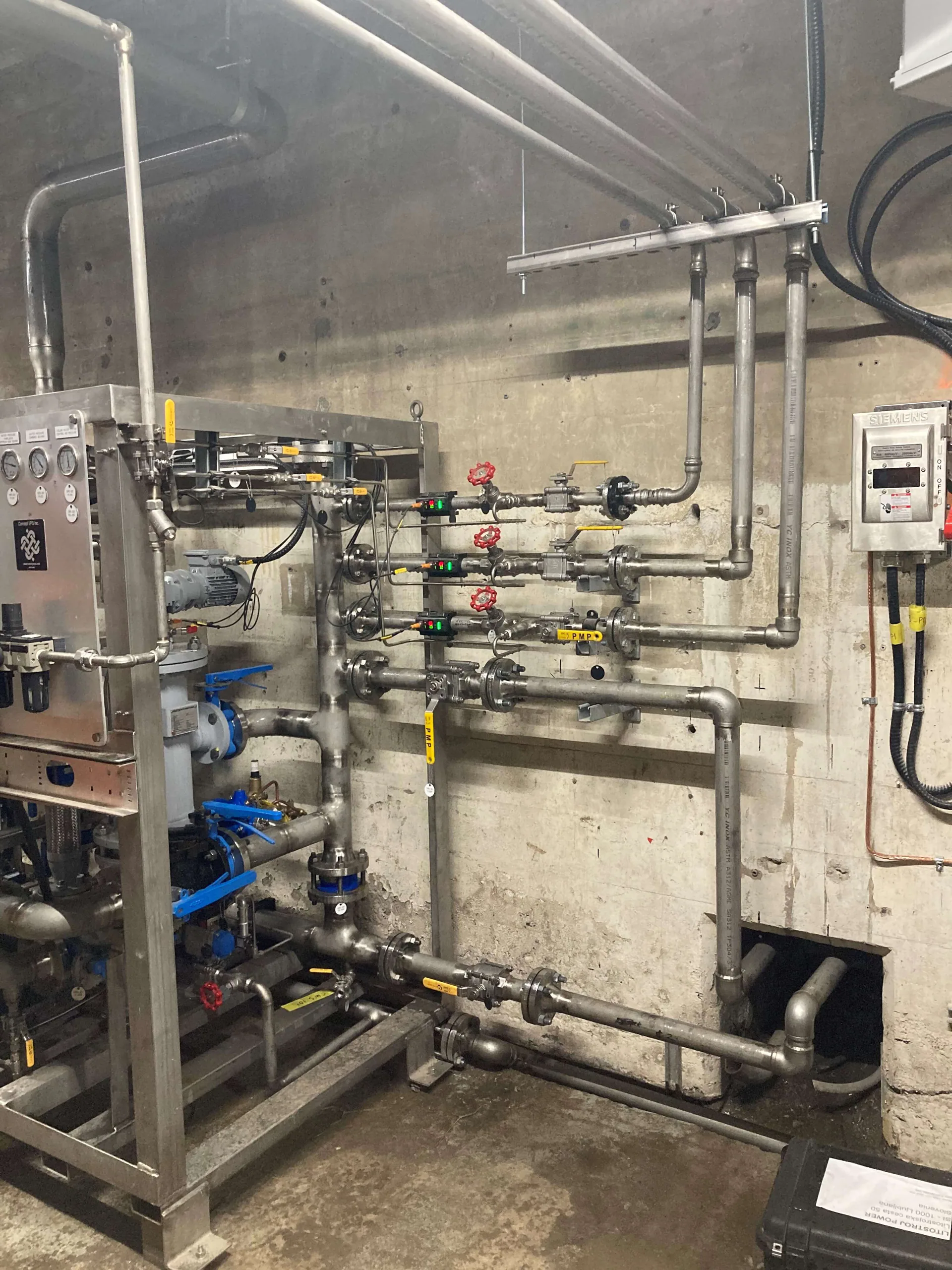 Tuyauterie de procédé en acier inoxydable et de petit diamètre, vannes, manomètres et unité compacte fixée à un mur de béton.