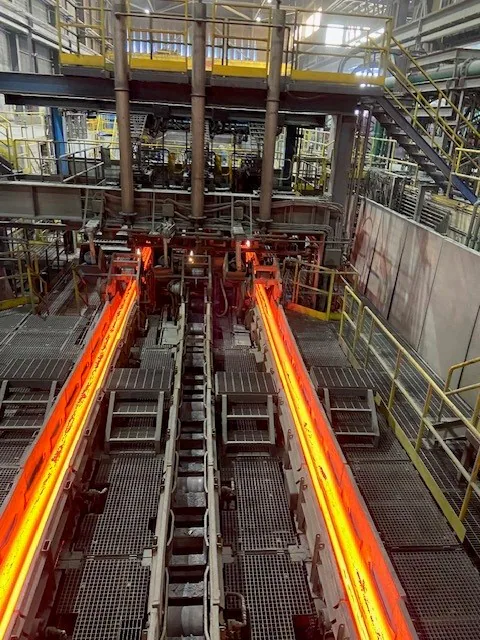 Ligne de production intérieure montrant deux brins d’acier incandescent avançant entre des rouleaux.